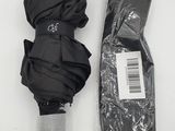 un parapluie noir et un sac noir posés sur une table blanche