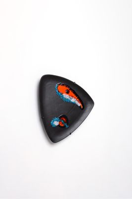 une assiette noire ornée d'un motif rouge et bleu
