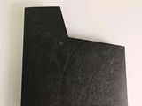 a close up of a piece of black paper on a white surface