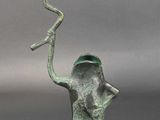 a statue of a frog holding a candle on a stand