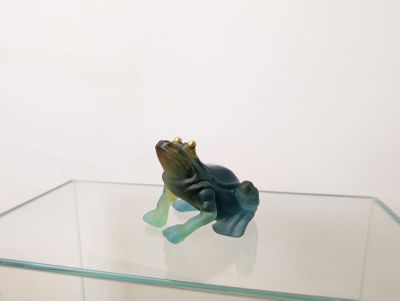 une petite figurine de grenouille posée sur une table en verre