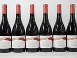six bottles of red wine lined up in a row on a table