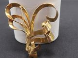 a gold brooch on a white cup on a table