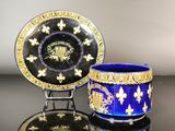 pair of royal blue and gold cups and saucers on a black table
