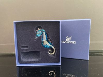 une boîte bleue contenant un porte-clés en forme de cheval
