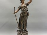 une statue antique en bronze représentant une femme tenant un arc, posée sur un socle