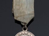 silver medal with an eye on it on a black surface