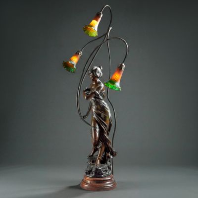 une statue en bronze représentant une femme tenant une lampe