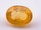 a close up of a yellow sapphire stone on a white surface