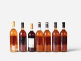 six bottles of wine are lined up in a row on a white surface