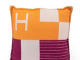un coussin orange et blanc orné d'un motif violet et blanc