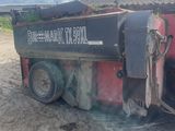 un camion noir et rouge garé sur un terrain en terre battue