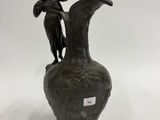 un vase noir surmonté d'une statue