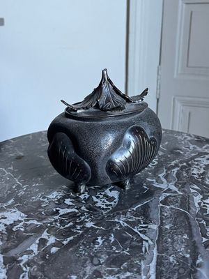 a black vase on a marble table with a door in the background