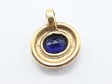 a close up of a gold pendant with a blue stone