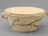 a large bowl with a handle and a flower design on it