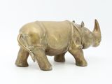 a small bronze rhino statue on a white surface
