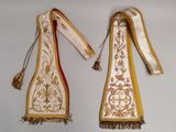 deux morceaux de tissu ornés de pompons, suspendus à un mur