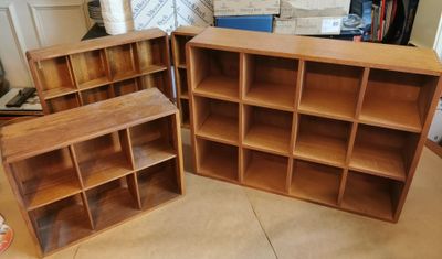 Dans une pièce, trois bibliothèques en bois sont empilées les unes sur les autres