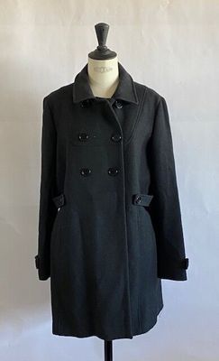 black peale coat on a mannequin stand against a white wall