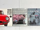 trois livres posés sur un mur blanc, avec une voiture rouge et une voiture noire