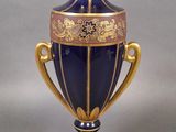 un vase bleu orné de motifs dorés, posé sur un socle