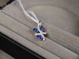 un petit pendentif en forme de losange bleu et blanc, présenté dans un écrin
