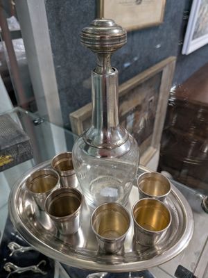 un plateau en argent sur lequel se trouvent des tasses en argent et une bouteille