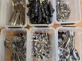 beaucoup de couverts dans des récipients en plastique posés sur une table