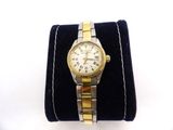 an image of a gold and silver wrist watch on a black velvet case