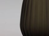 a brown glass vase with a black base on a table
