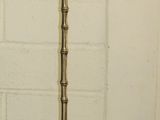 a tall brass floor lamp with a glass shade on it