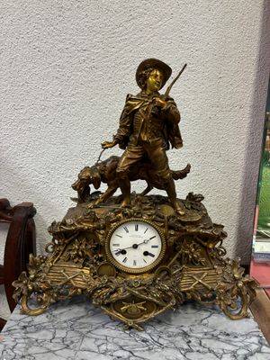 une statue représentant un homme avec un chien et une horloge posée sur une table