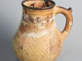 a brown vase with a handle on a gray surface