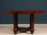 a round dining table with four legs and a wooden top