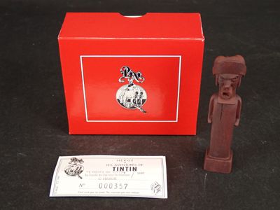 une petite figurine en chocolat à côté d'une boîte rouge