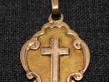 un gros plan d'une croix sur un pendentif en or posé sur un tissu noir