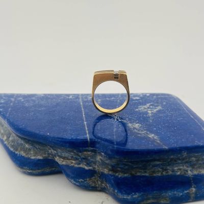 a close up of a gold ring sitting on top of a blue stone