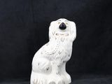 une statue de chien blanc posée sur une surface noire