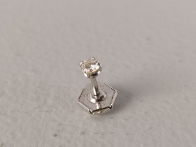 un gros plan d'une boucle d'oreille à diamant unique sur une surface blanche