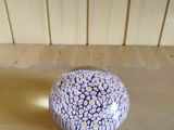purple and white flowered paperweight sitting on a wooden table