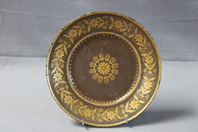 a brown and gold plate with a flower design on it