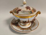un plateau blanc et doré sur lequel sont posés une tasse et une soucoupe