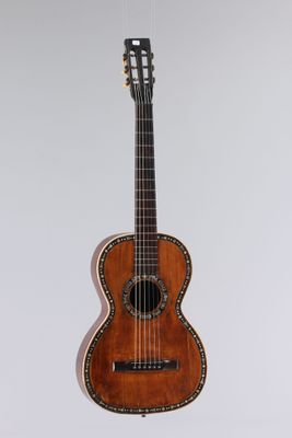 an old guitar hanging on a wall with a white background