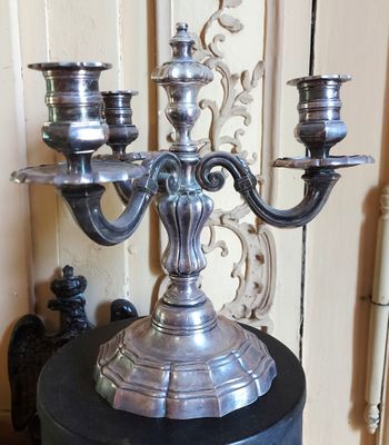 un candélabre en argent avec trois bougies posé sur une table noire