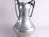 un vase en argent posé sur une surface blanche
