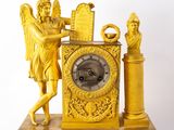 a gold clock with an angel on top of it