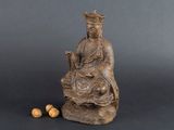 une statue représentant une femme assise sur un rocher, avec des noix devant elle