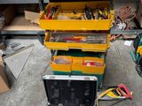 une boîte à outils jaune contenant des outils, posée par terre