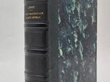 un livre noir à la couverture verte posé sur une surface blanche